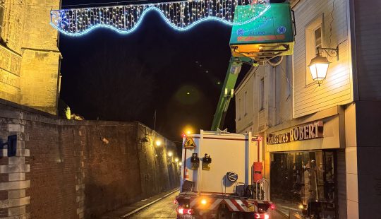 Une équipe d'électricien de Cegelec installe une guirlande lumineuse pour Noël dans une rue de nuit