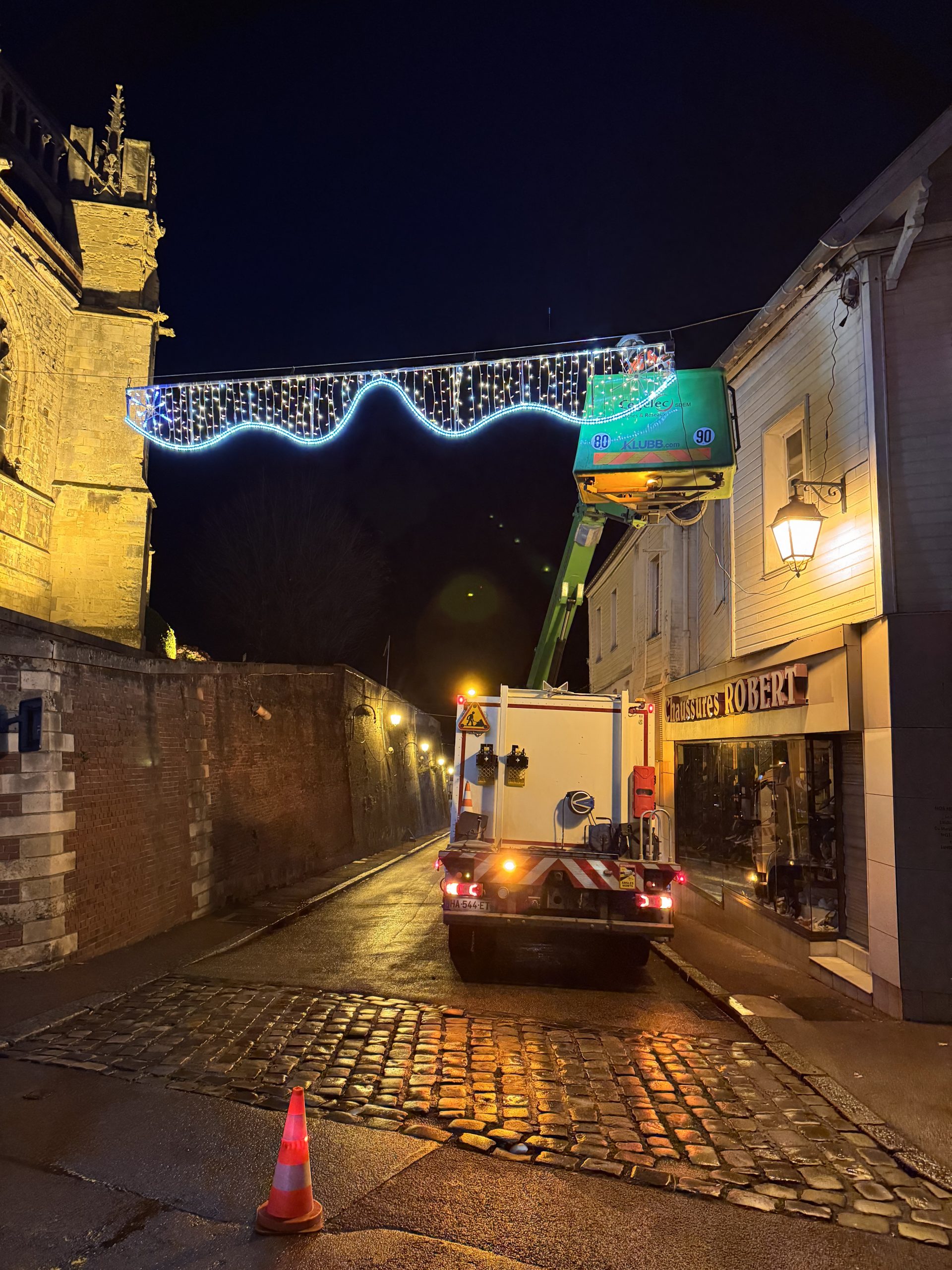 Une équipe d'électricien de Cegelec installe une guirlande lumineuse pour Noël dans une rue de nuit